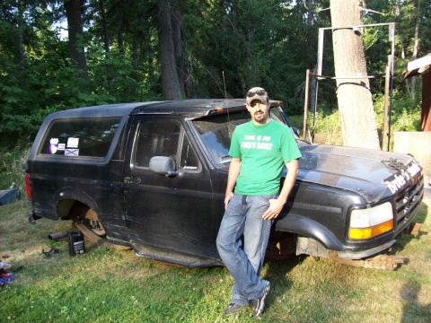 1995 Ford Bronco - A man stands next to a black Ford Bronco that is missing its rear wheels and appears to be undergoing repairs.