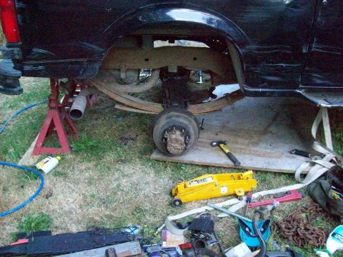 1995 Ford Bronco - The rear suspension and axle are exposed, with tools and equipment laid out on the ground.