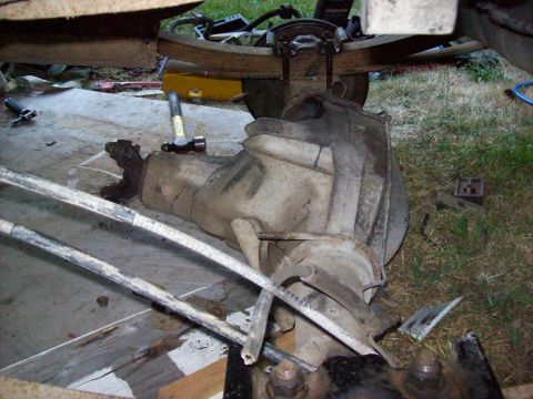 1995 Ford Bronco - The rear axle assembly of a vehicle is shown removed from the chassis, resting on the ground with tools present.