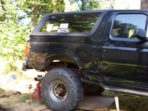 1995 Ford Bronco - This black Ford Bronco is shown from the side, lifted with large tires and aftermarket step bars.