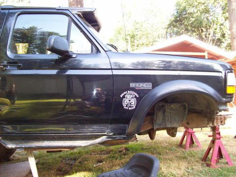 1995 Ford Bronco - This black Ford Bronco is shown from the side, lifted on jack stands, with an off-road sticker on the door.