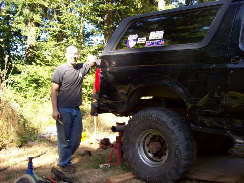 1995 Ford Bronco - Man poses with his lifted 1995 Ford Bronco, showing off its off-road tires and stance.