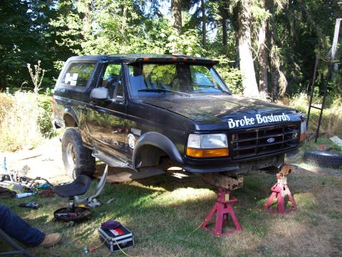 1995 Ford Bronco - This black 1995 Ford Bronco is elevated on jack stands, with "Broke Bastards" text visible on its hood.