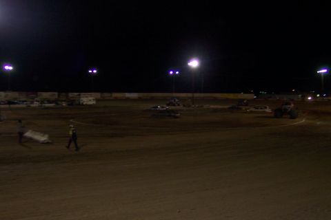 1995 Ford Bronco - A dirt track scene at night, illuminated by stadium lights, with several vehicles and individuals present on the track.