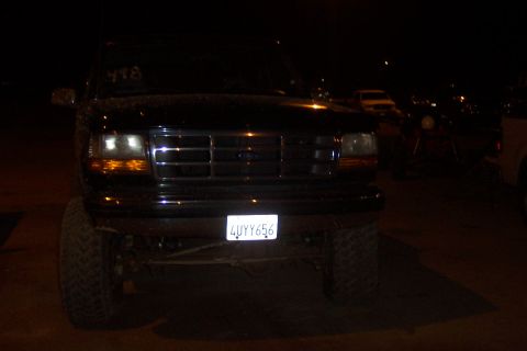 1995 Ford Bronco - Front view of a black Ford Bronco at night, showing its grille and large tires.