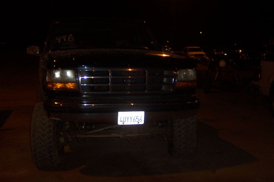 Black Ford Bronco front view at night. Large tires, chrome grille, and license plate 4UYY656 are visible