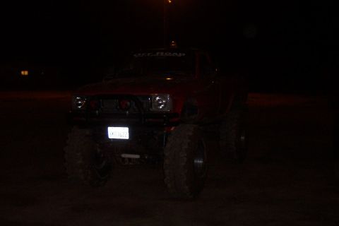 1995 Ford Bronco - A red lifted truck is seen at night with its headlights on and a custom grille.