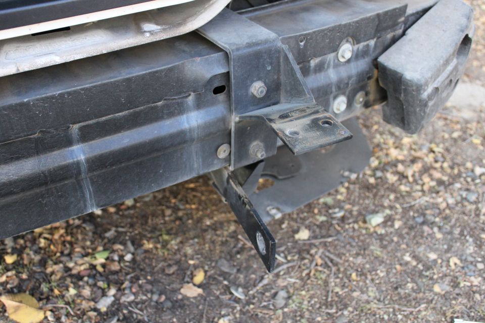 Underside of vehicle front bumper showing mounting bracket and bolts