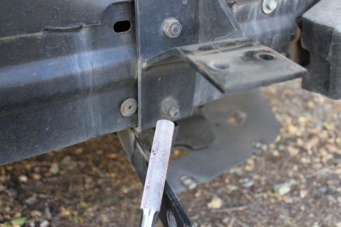 2003 Ford Crown Victoria - Detail of a vehicle's chassis and mounting hardware, with a tool engaged on a bolt.