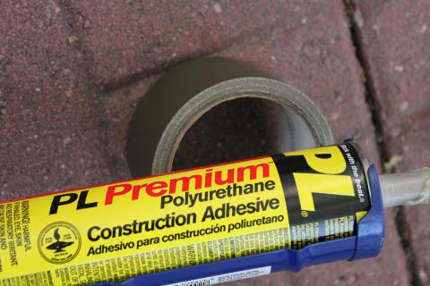 2003 Ford Crown Victoria - Construction adhesive and duct tape are shown close-up on a brick-like surface.
