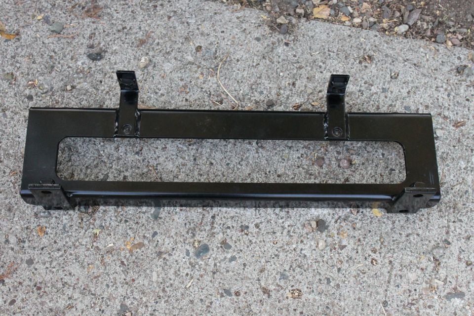 Black-painted steel bumper mounting crossmember bracket on pavement