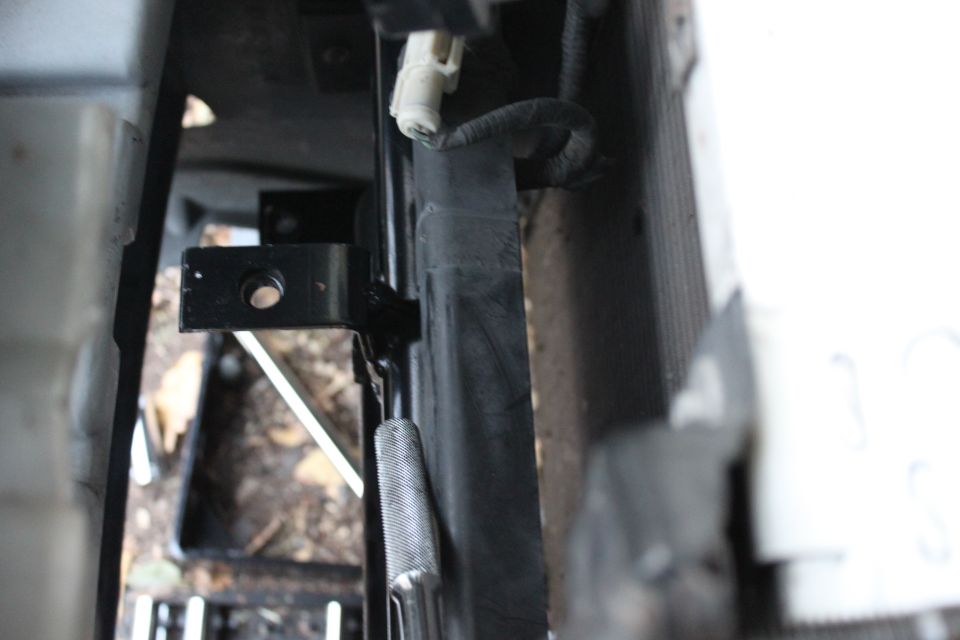 Close-up of vehicle frame rail bracket and wiring near radiator support underbody