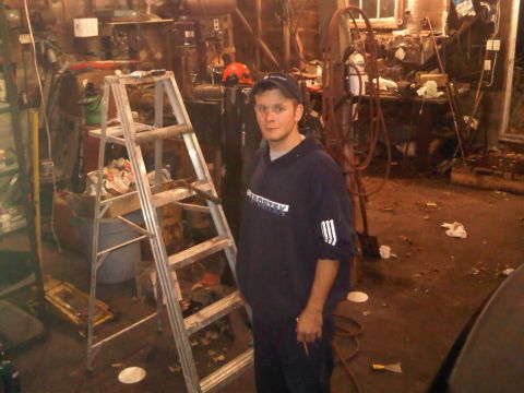 2003 Ford Crown Victoria - A man is standing in a workshop filled with various tools and equipment.