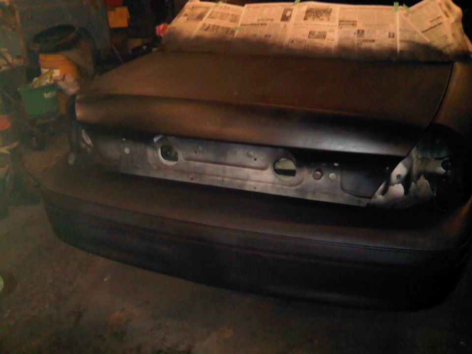 Rear of a 2003 Ford Crown Victoria with trunk lid covered in newspaper, preparing for paint