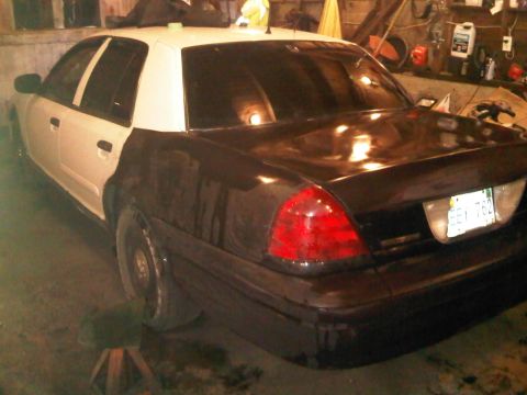 2003 Ford Crown Victoria - This 2003 Ford Crown Victoria police car, seen from the rear, has a white top and black lower body, with license plate EEJ 762 visible.