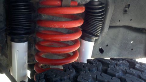 1988 Ford Bronco - Close-up view of a vehicle's suspension system, showing a red coil spring and shock absorber.