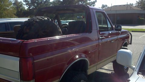 1988 Ford Bronco - This 1988 Ford Bronco is seen from the 3/4 front angle, with a large spare tire visible in its cargo bed.