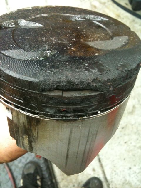 1990 Ford Bronco - A damaged piston shows significant carbon deposits and wear on its top ring land.