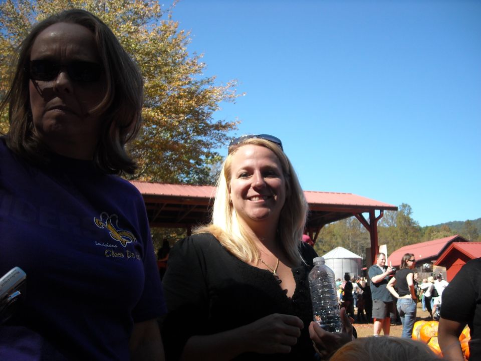 Woman in purple shirt and woman in black shirt smiling outdoors with buildings and trees in background