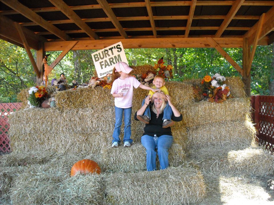 Burt's Farm sign above hay bales with pumpkin and people