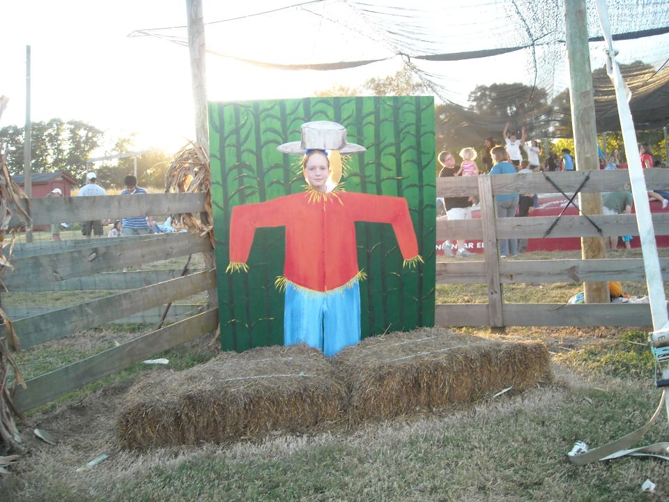 Scarecrow cutout with a person in a cornfield scene at a fall festival