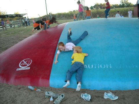 1979 Ford F-150 - Kids play on a large inflatable cushion at an outdoor event, with shoes scattered on the sand below sand below.