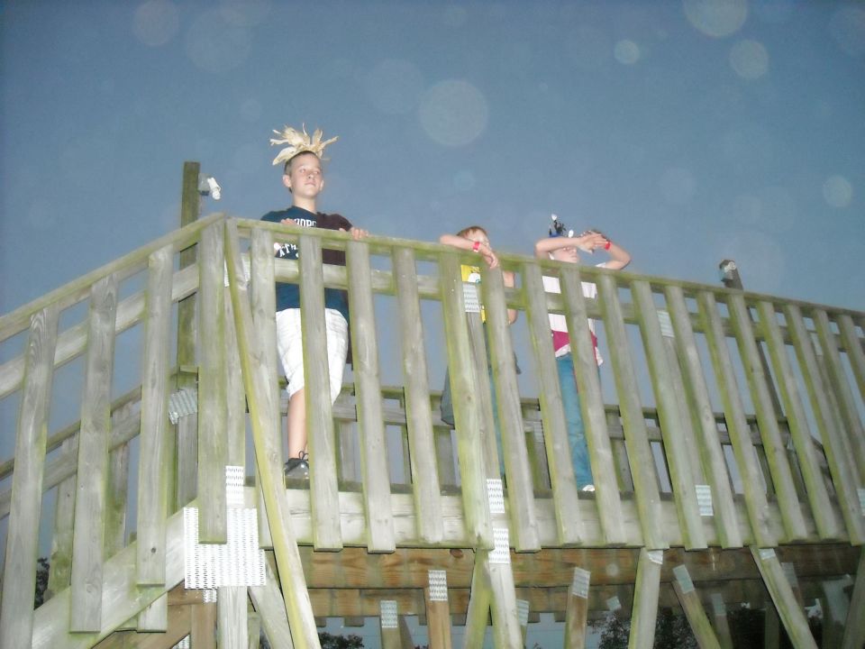 Children stand on a wooden deck against a dark sky