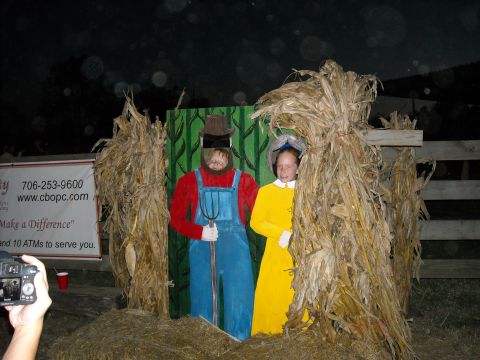 1979 Ford F-150 - A photo booth with cardboard cutouts of a farmer and a girl is set up with hay bales and corn stalks.