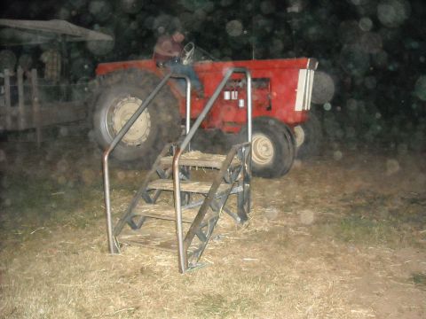 1979 Ford F-150 - A person is seated in a large red tractor, with a set of stairs positioned before it.