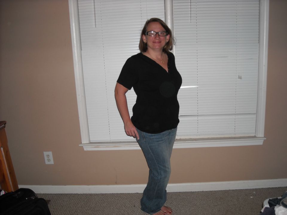 Woman in black shirt and blue jeans standing indoors