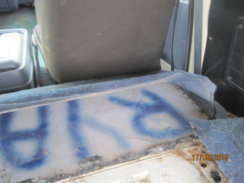 Close-up of blue graffiti on the floor of a vehicle interior, near the seats