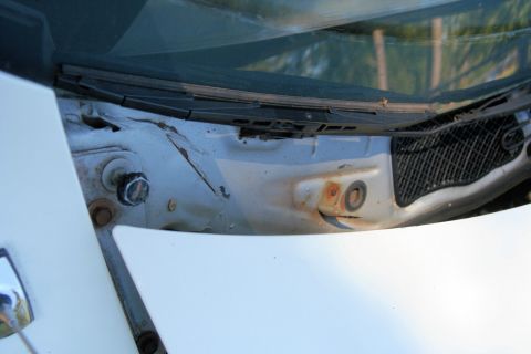 1976 Ford Ranchero - The cowl area of a car shows signs of rust and a wiper assembly.