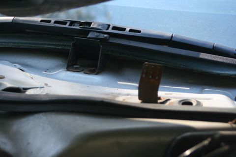 1976 Ford Ranchero - Detail of the cowl panel below the windshield with the hood open, showing black wiper arms and blades across the glass, a bolted black brac…