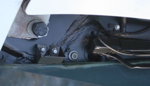 1976 Ford Ranchero - Tight detail of the cowl area under a raised hood, showing a black-painted panel with seam sealer beads, a bolted-on black bracket, phillip…