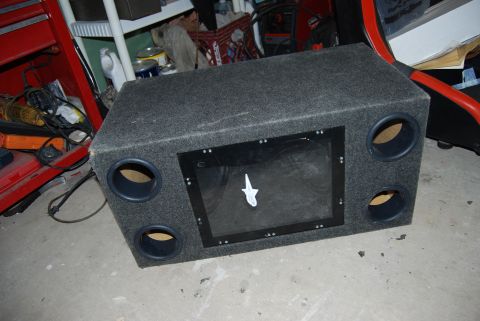 1982 Ford Bronco - A car subwoofer enclosure sits on a concrete floor next to a red toolbox and other garage items.