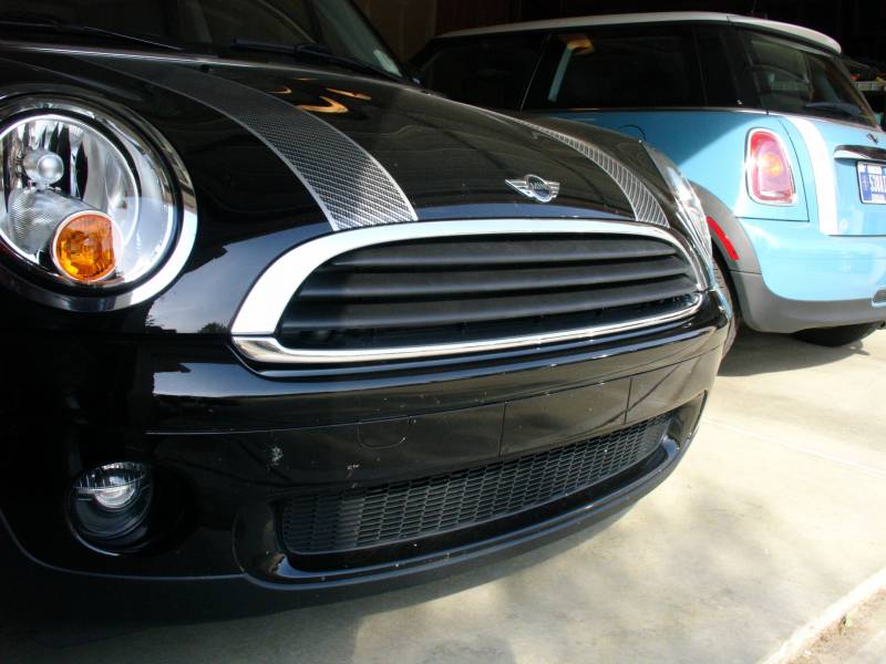 Black MINI Cooper front end with chrome grille beside a light-blue MINI