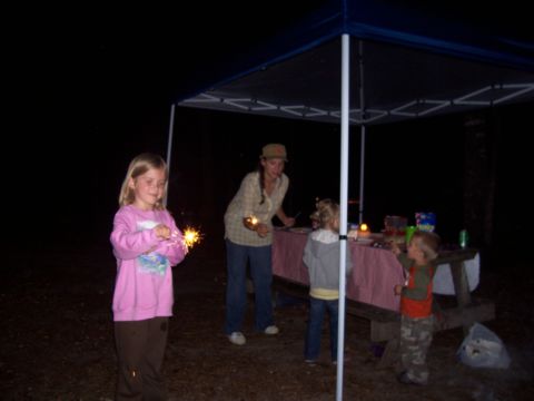 1994 Ford Bronco - A family enjoys sparklers at a nighttime gathering under a canopy.