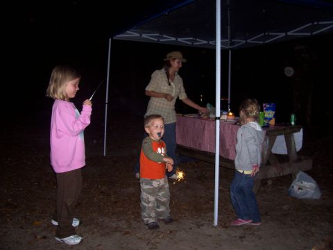 1994 Ford Bronco - Family enjoys sparklers at a campsite gathering under a canopy at night.