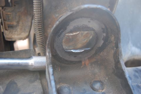 1982 Ford Bronco - A socket wrench extension is inserted into a worn metal bracket, suggesting mechanical work.