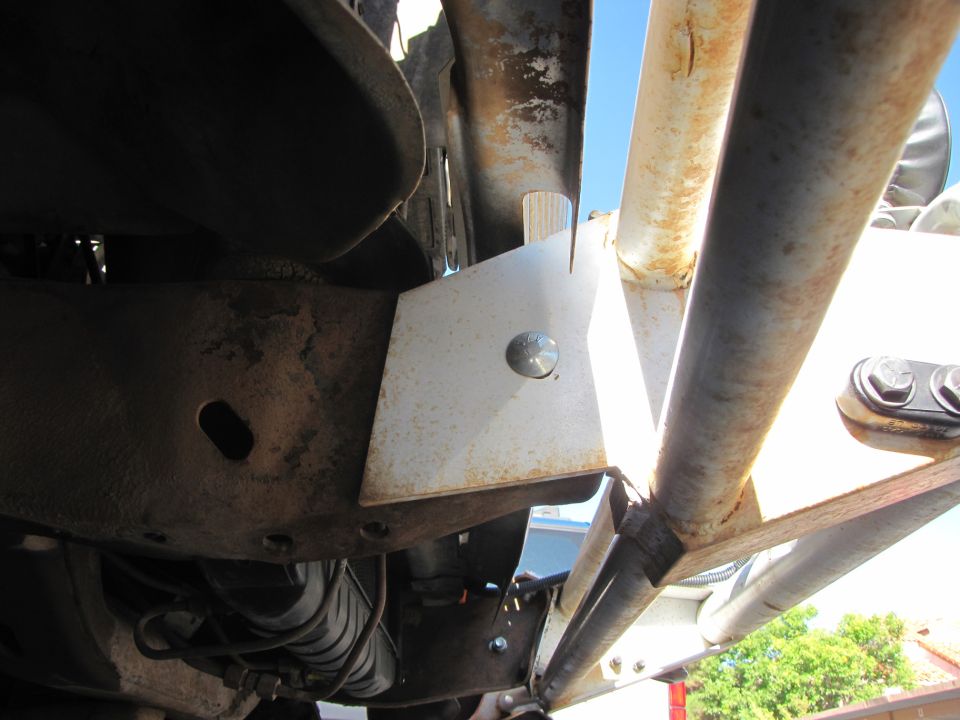 Close-up of vehicle frame with added bracket and roll cage tubing. Supermotors.net logo visible