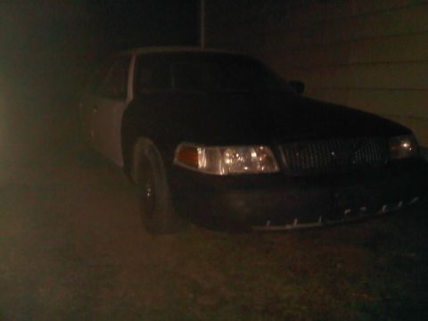 2003 Ford Crown Victoria - A 2003 Ford Crown Victoria is seen from the front at night, its grille and headlights illuminated.