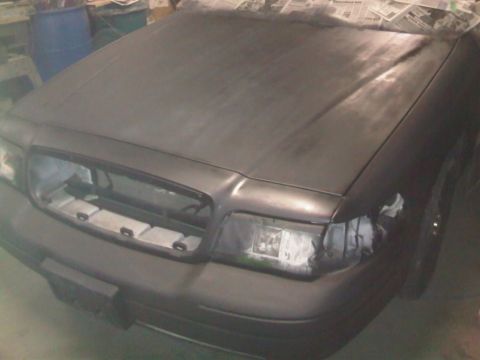 2003 Ford Crown Victoria - Front view of a 2003 Ford Crown Victoria in primer, with the grille removed and headlights covered.