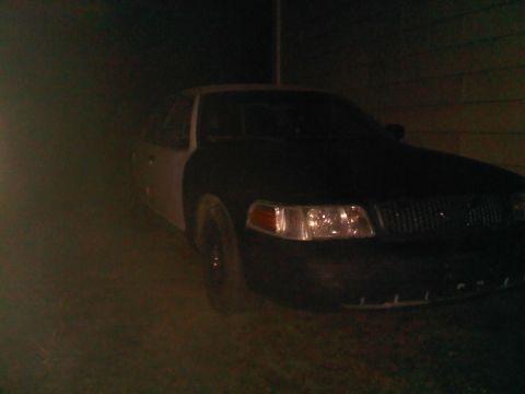 2003 Ford Crown Victoria - A dark Ford Crown Victoria is parked outside at night, showing its front end.
