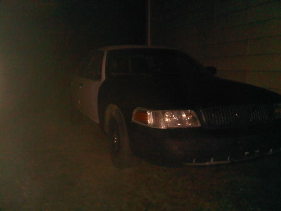 Front view of a 2003 Ford Crown Victoria, dark colored hood and fenders