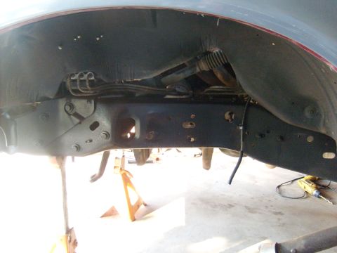 1986 Ford Bronco - The vehicle's undercarriage is supported by jack stands, revealing the frame and suspension system.