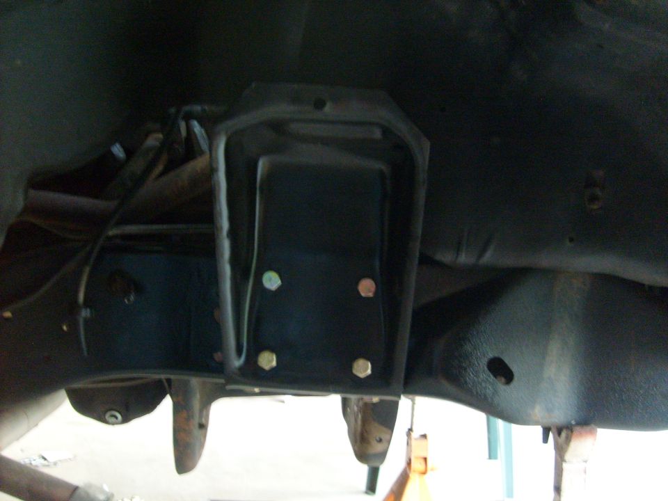 Close-up of a vehicle's undercarriage, showing a metal bracket bolted to the frame