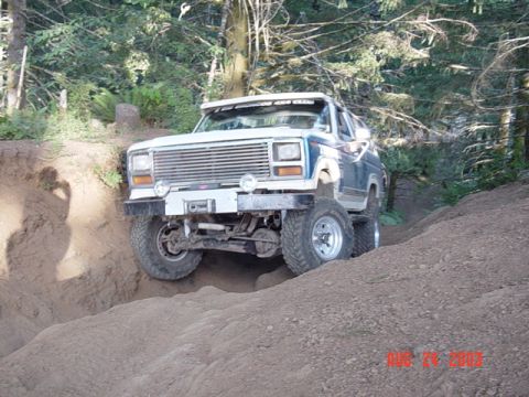 1989 Ford Bronco - This modified Ford Bronco navigates a steep dirt incline on a wooded trail.