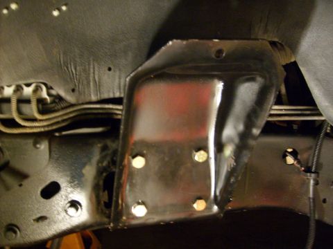 1986 Ford Bronco - Close-up view of a vehicle's undercarriage, focusing on a metal bracket attached to the frame.