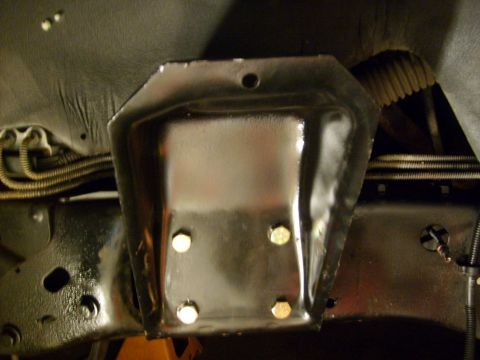 1986 Ford Bronco - Close-up view of a black metal bracket attached to the vehicle's frame, with visible bolts and wiring.