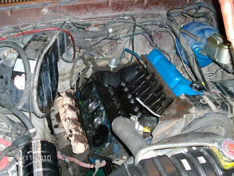 1979 Ford F-150 - Engine bay view showing an exposed engine block, likely due to a blown head gasket, with blue valve covers and various hoses and wires.
